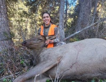 Female hunter with her cow elk in the trees